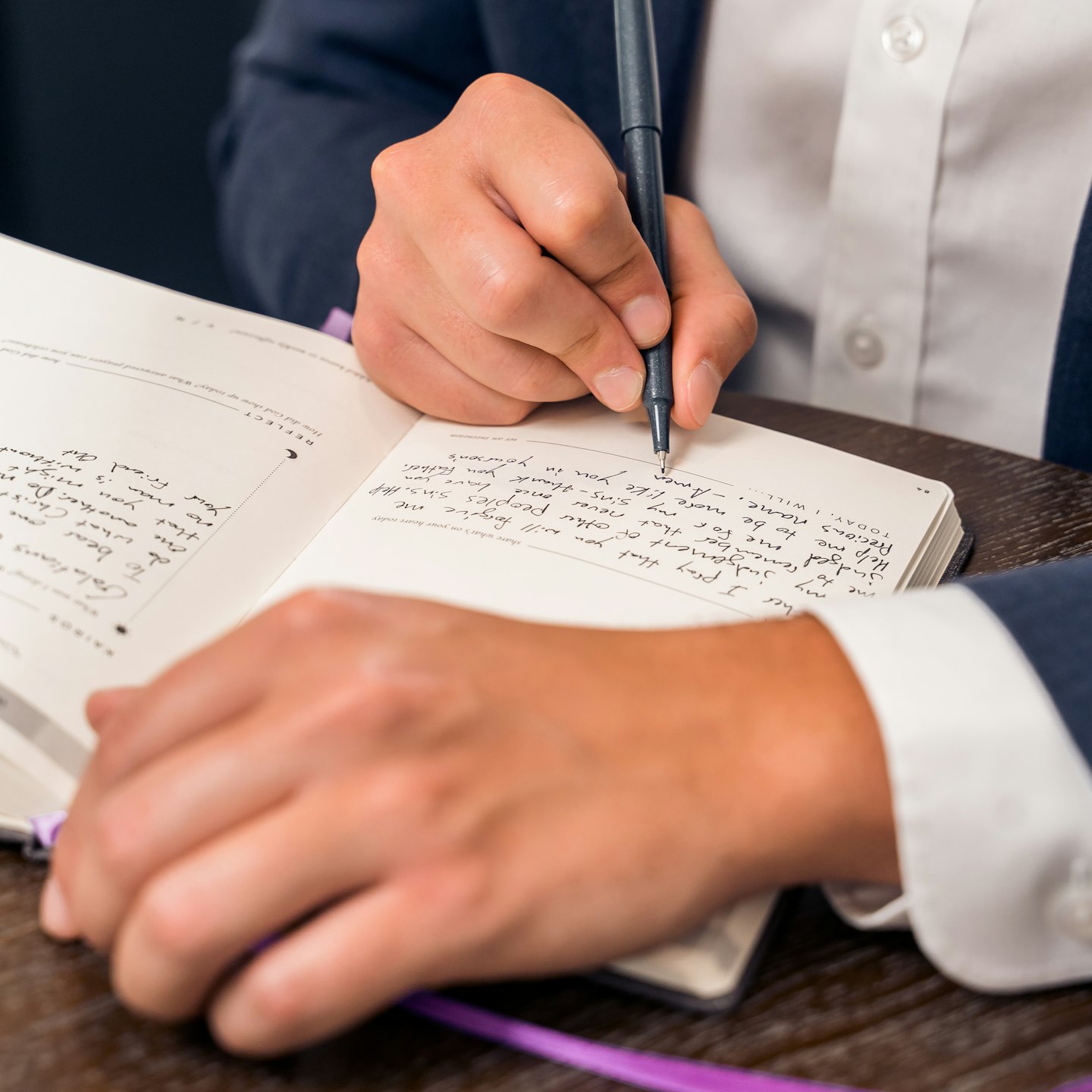 Persoon die met een pen in een dagboek schrijft.